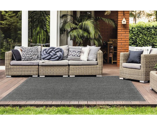 Buitenscène met rotan zithoek en grijs tapijt op een houten terras