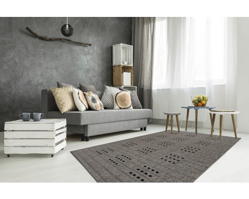 Moderne woonkamer met grijze bank, sierkussens, houten kistenmeubels en een tapijt met patroon