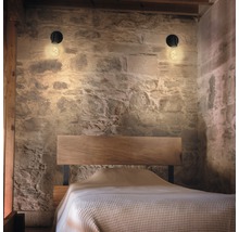 Slaapkamer met houten bed, metselwerk en twee wandlampen
