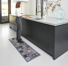 Vrouw staat in de keuken op een keukenmat met patroon.