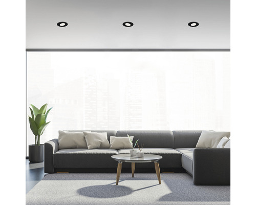 Woonkamer met grijze hoekbank, vloerkleed en inbouwspots