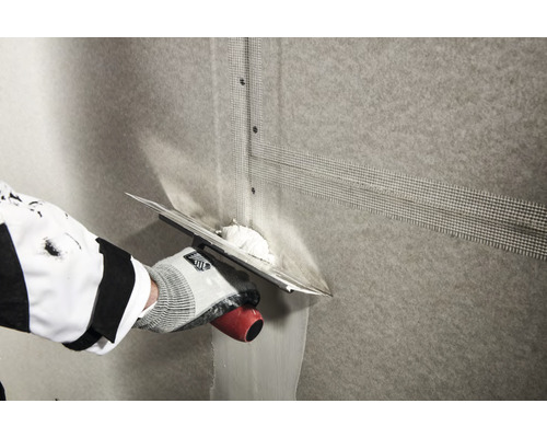 Verwerking van wapeningsweefsel op een muur met een spaan.