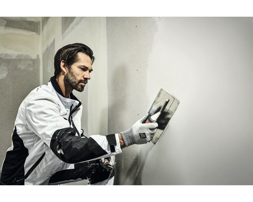 Vakman egaliseert een muur met een pleisterspaan.