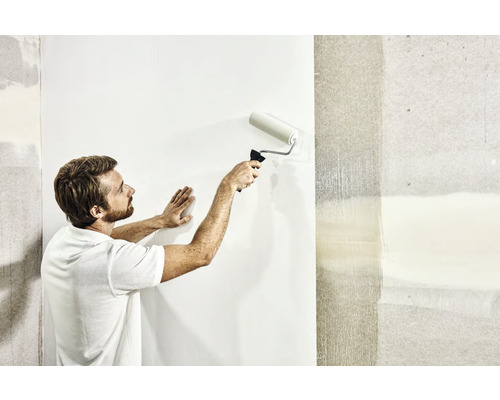 Een man behangt een muur met een verfroller.