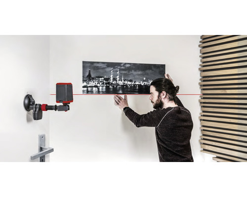 Man richt een foto uit met een laserwaterpas op de muur.
