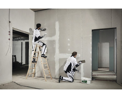 Twee vakmensen plamuren een gipsplaatwand in een ruwbouw.