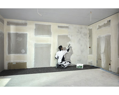 Interieur met vakman die een muur plamuurt