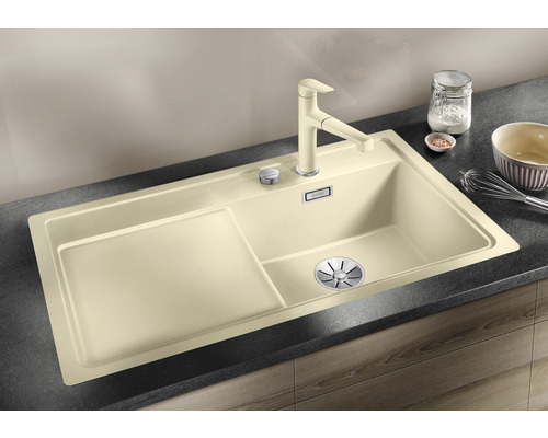 Beige aanrechtspoelbak met afdruiprek en kraan op een aanrecht
