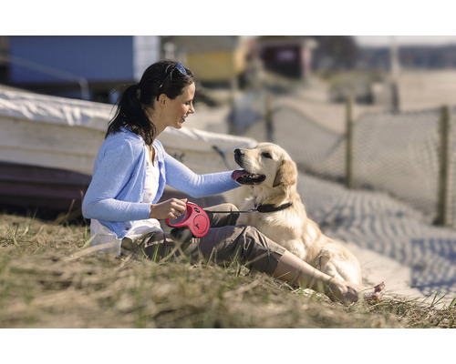 Vrouw aait hond met rollijn op het strand