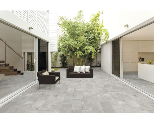 Licht terras met grijze vloerplaten, zitmeubelen en beplanting