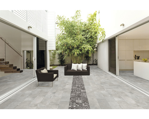 Terras met grijze vloertegels, zitmeubels en beplanting