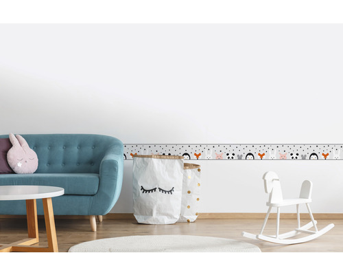 Kinderkamer met bank, tafel, speelgoed en rand met dierenmotieven