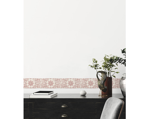 Decoratieve rand met bloemmotief op een muur boven een zwart bureau