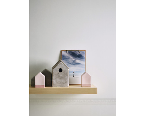 Decoratieve huisjes en een afbeelding op een houten plank aan een muur.