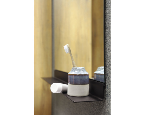 Tandenborstel in beker op een plank in de badkamer