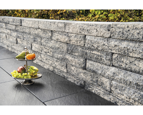 Muur van grijze stenen met fruitschaal op donkere vloerplaten