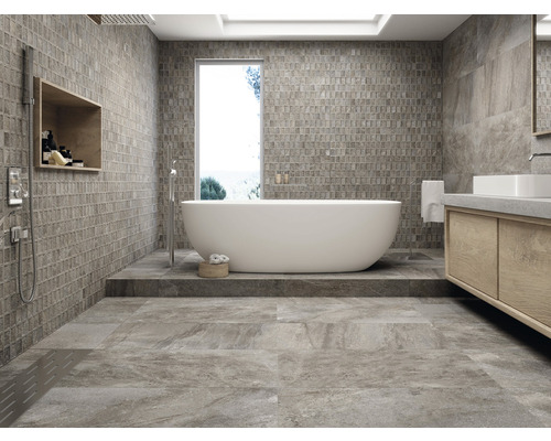 Lichte badkamer met bad, wastafel en betegelde wanden en vloer.