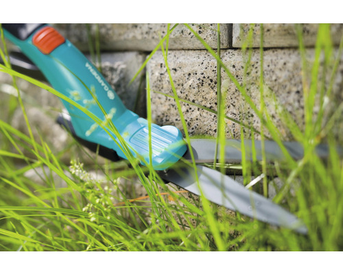 Gardena grasschaar in gras voor een stenen muur