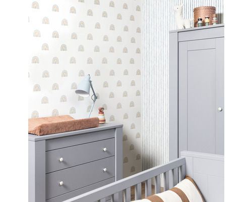 Een kinderkamer met een commode, een kledingkast en een muur met een regenboogpatroon.