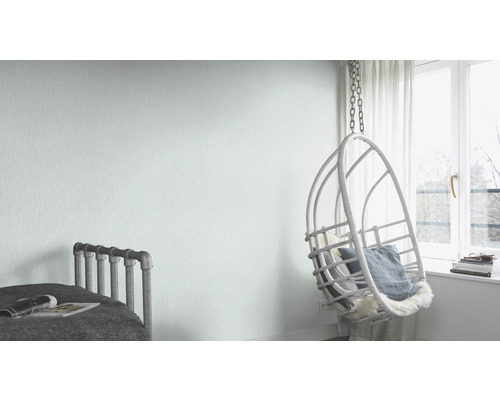 Lichte kamer met bed, hangstoel en lichtgroen vliesbehang