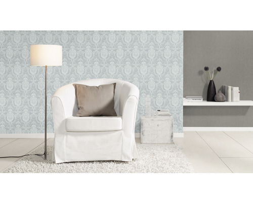 Woonkamer met fauteuil, staande lamp en behang met motief