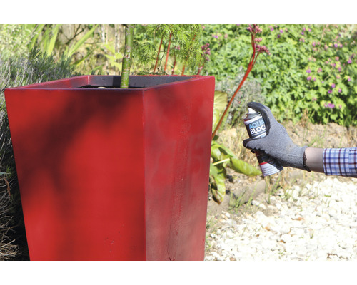 Iemand spuit een bloemenzuil in met impregneermiddel.