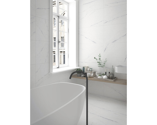 Moderne badkamer met wit bad, kraan en wandtegels in marmerlook