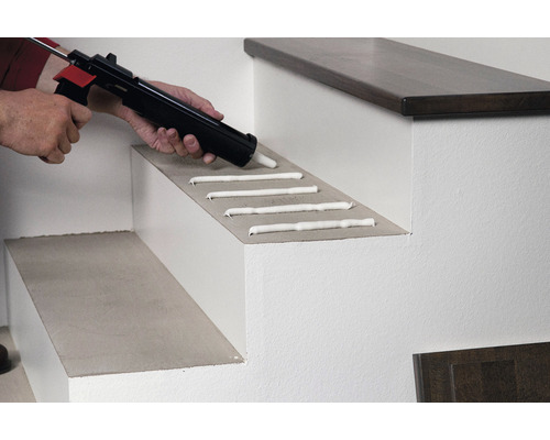 Aanbrengen van lijm op een traptrede met een kitpistool.