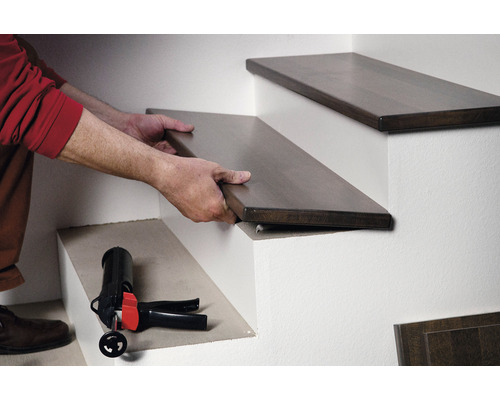 Man monteert houten trap trede met montagelijm