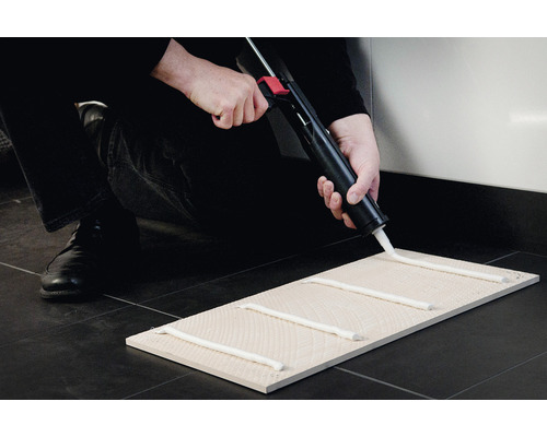 Montagekit aanbrengen op een tegel met een kitspuit.