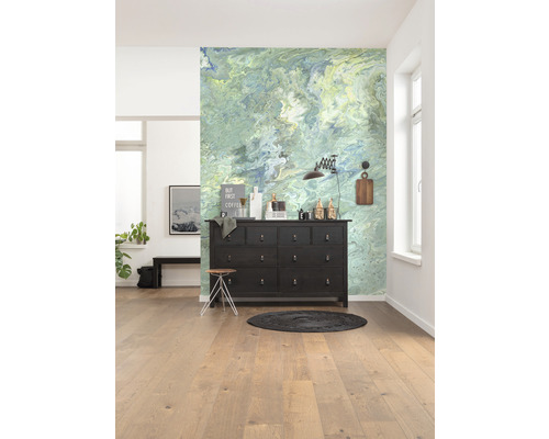 Lichte kamer met patroonwand, donkere commode en houten vloer