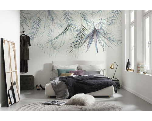 Slaapkamer met een bed, een vloerkleed en een wand met bladerenbehang