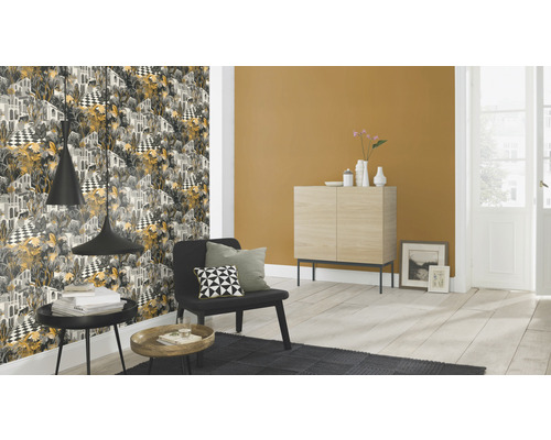 Woonkamer met patroonbehang, fauteuil en bijzettafels.