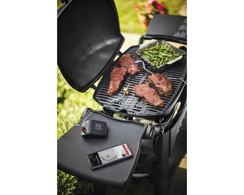 Barbecuescène met steaks, groene groenten, barbecue thermometer en smartphone op een barbecue