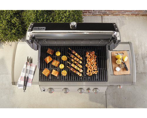 Weber barbecue met gegrilde gerechten zoals vis, citroenen, spiesen en garnalen.