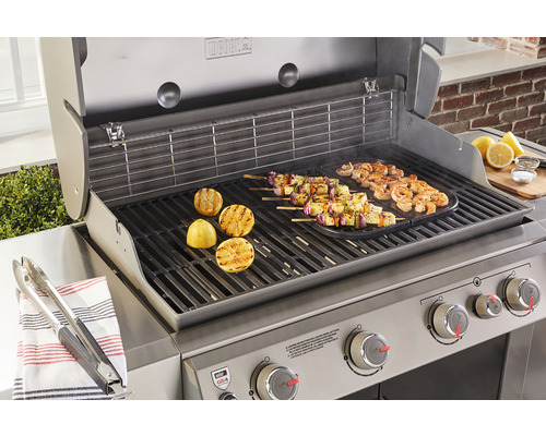 Weber barbecue met gegrilde etenswaren en citroenen op het rooster