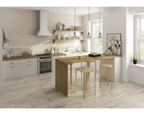 Lichte keuken met tegelvloer, keukenblok, eethoek en ramen voor natuurlijk licht.