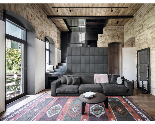 Woonkamer met bank, tapijt en bakstenen muur