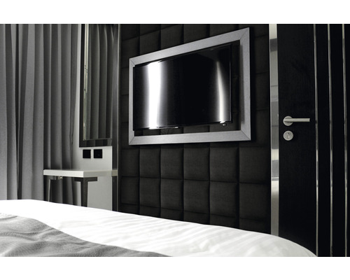 Slaapkamer met gestoffeerde wand, televisie en nachtkastje