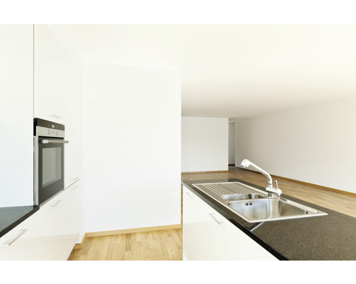 Lichte keuken met roestvrijstalen spoelbak, kraan en inbouwoven.