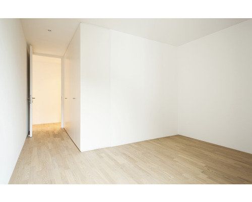 Lichte kamer met houten vloer, witte muur en openstaande deur