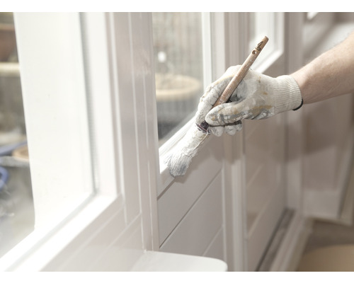 Iemand schildert een raamkozijn met een penseel.
