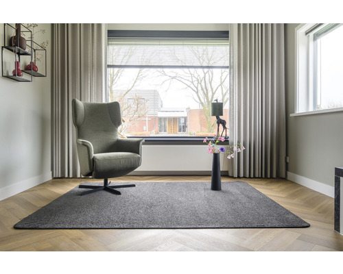 Woonkamer met fauteuil, tapijt en raamdecoratie
