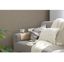 Grijze bank met kussens, een beker en een houten plank.