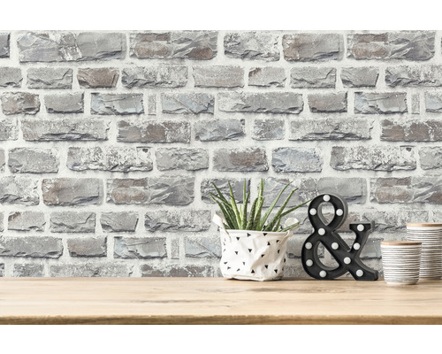 Decoratief behang in steenlook op een muur met plant, decoratief &-teken en decoratieve blikken op een tafel