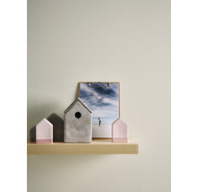 Decoratieve huisjes van beton en hout op een plank met een foto op de achtergrond