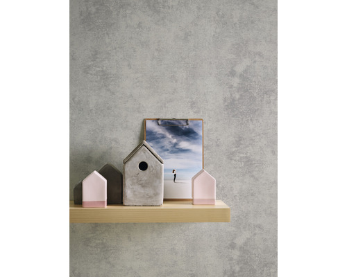 Decoratieve huizen van beton en hout op een plank voor een grijze muur.