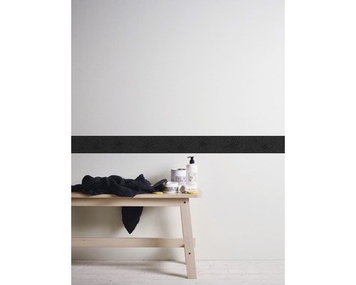 Decoratieve wand met sierrand, handdoek en verzorgingsproducten op een houten bank