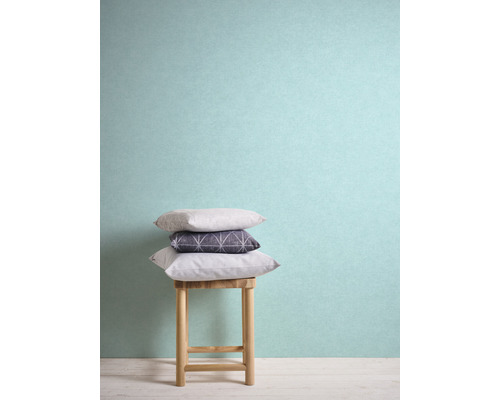 Stapel kussens op een houten kruk voor een muur