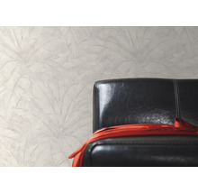 Wanddecoratie met bladmotief naast een zwarte leren fauteuil